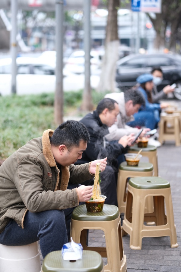 12月2日，南岸區銅元局長江村，街頭一小面館，市民在路旁吃面。郭旭攝