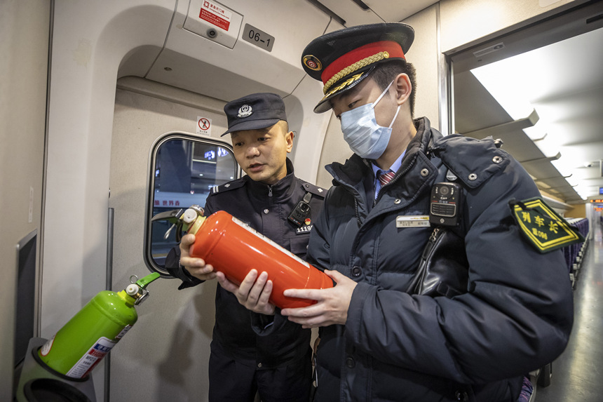 彭聰（左一）在列車長的配合下，對列車配備的滅火器進行檢查。胡勇攝