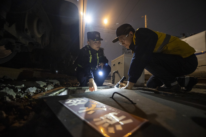 彭聰（左一）在重慶北動車所工作人員的配合下，對存車場的地下式室外消火栓進行檢查。胡勇攝